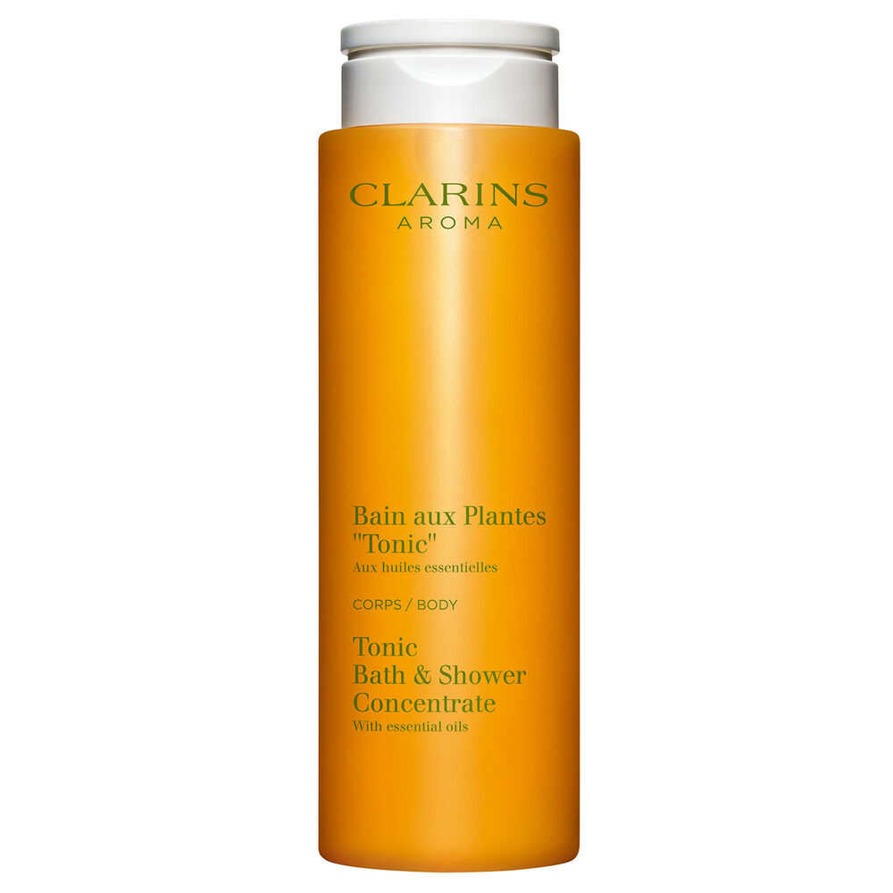 Packshot of Clarins Tonic Bath and Shower Concentrate gel, close to some mint and rosemary leaves on a orange background.