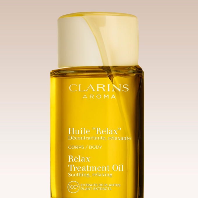 Packshot of Clarins Relax Body Treatment Oil on a textured background, with text emphasising the relaxing power of the product
