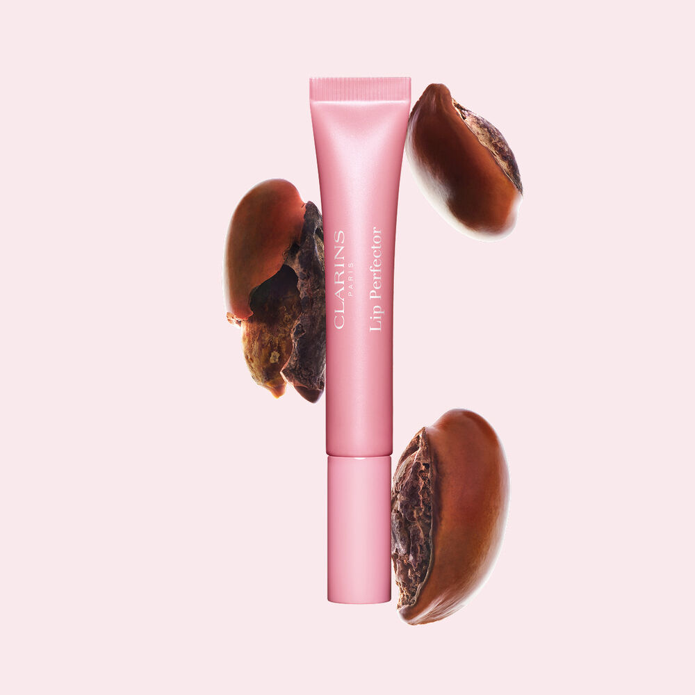 Plumping lip perfector tube shown with raw shea seeds to highlight the intense lip care formula for deep nourishment effect
