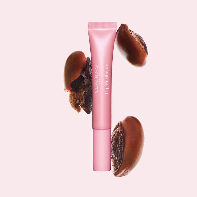 Plumping lip perfector tube shown with raw shea seeds to highlight the intense lip care formula for deep nourishment effect