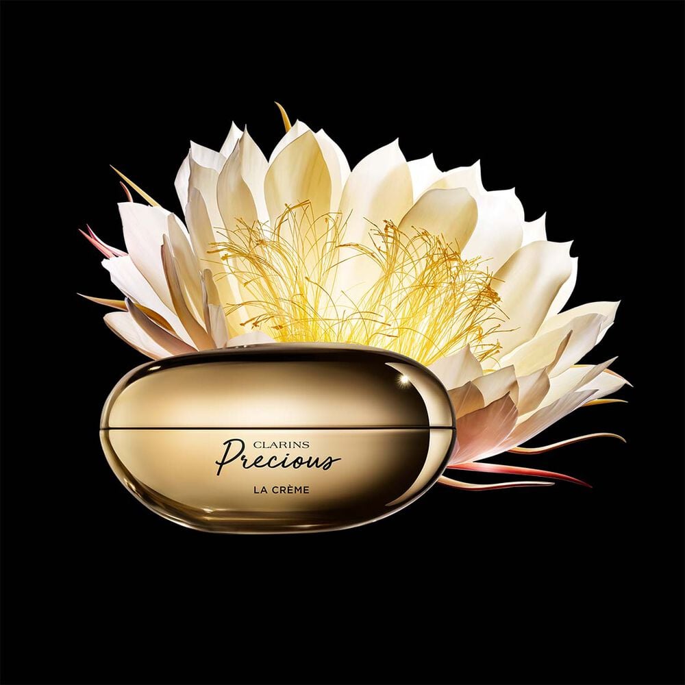 Packshot of Clarins Precious Soft Cream close to a Moonlight flower on dark background.