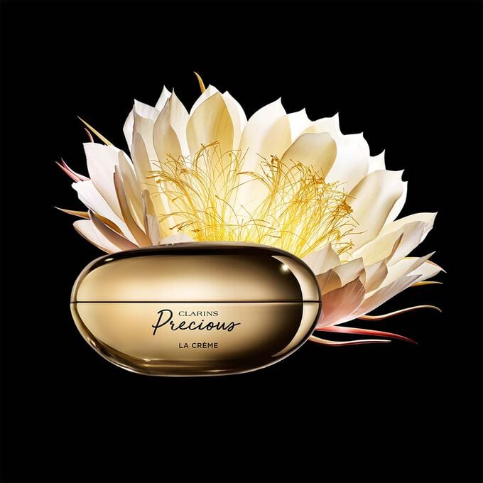 Packshot of Clarins Precious Soft Cream close to a Moonlight flower on dark background.