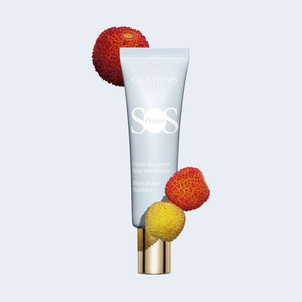 Packshot of a tube of SOS Primer Mattifying by Clarins, among strawberries and other fruits, to blur pores and reduce shine.