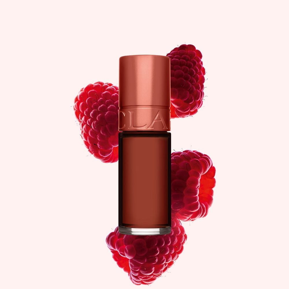 Packshot of Clarins Brown Water Lips Stain in shade 13, placed beside rasberries on a light Brown background.