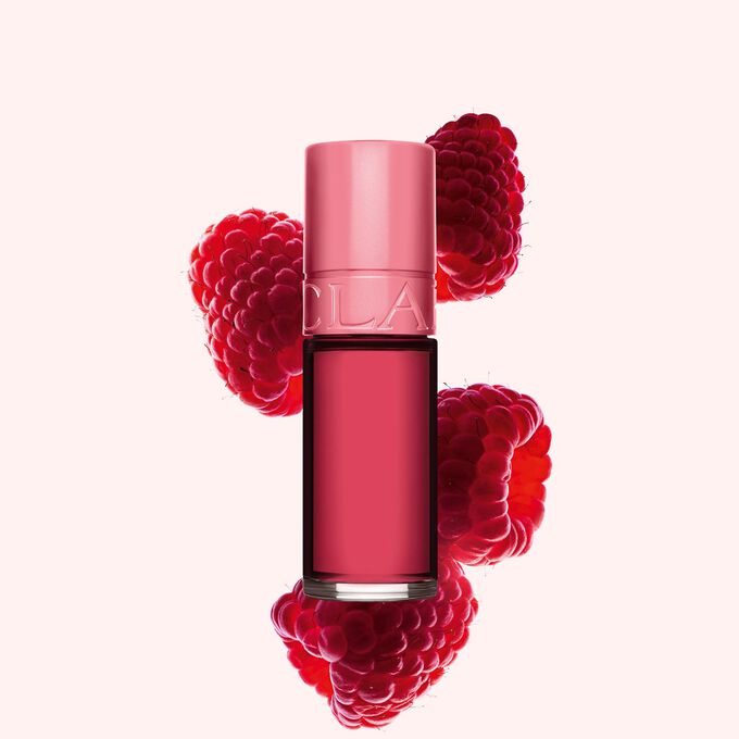 Packshot of Clarins Pink Water Lips stain in shade 11, placed beside rasberries on a light pink background.