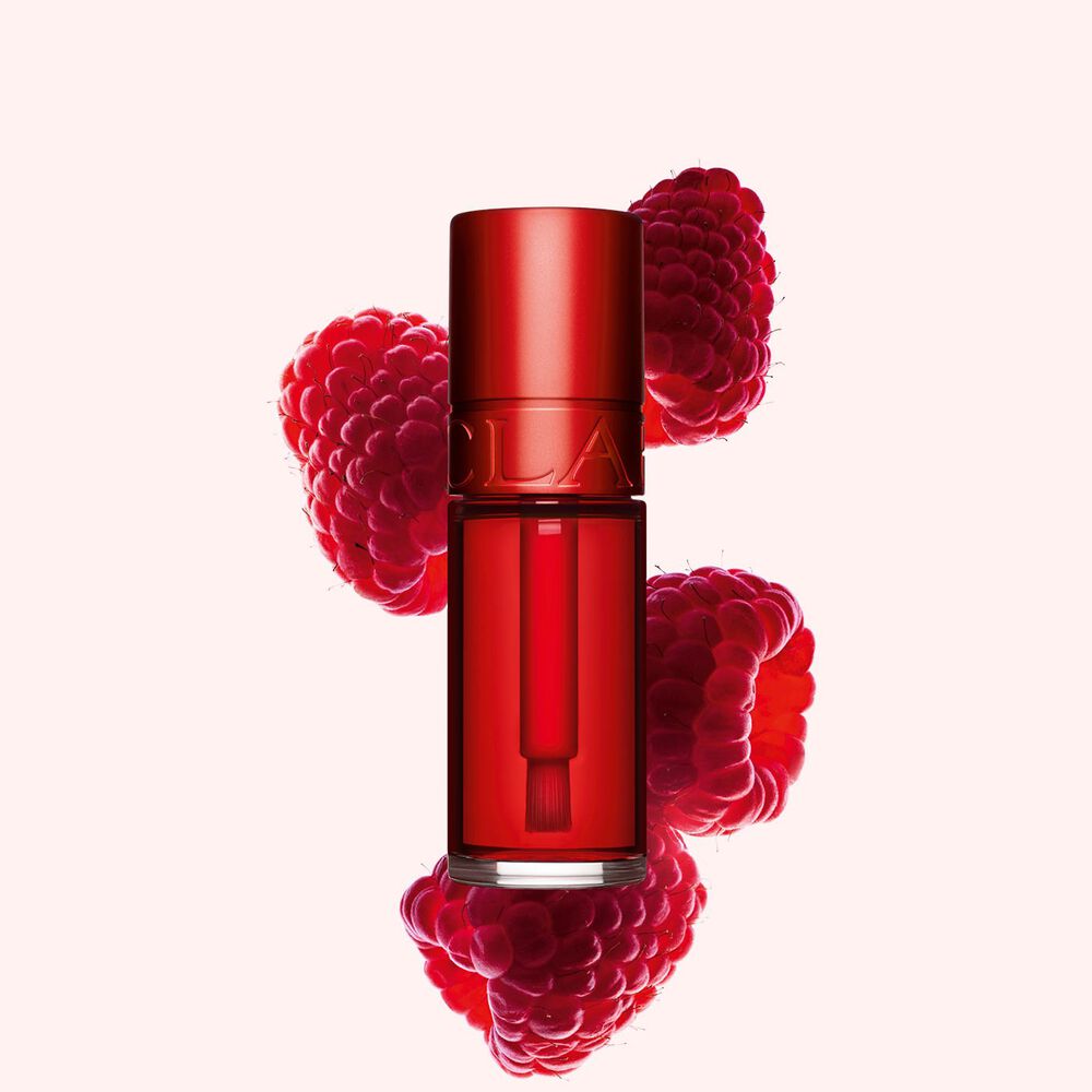 Packshot of Clarins Red Water Lip Stain in shade 03, placed beside rasberries on a light pink background.