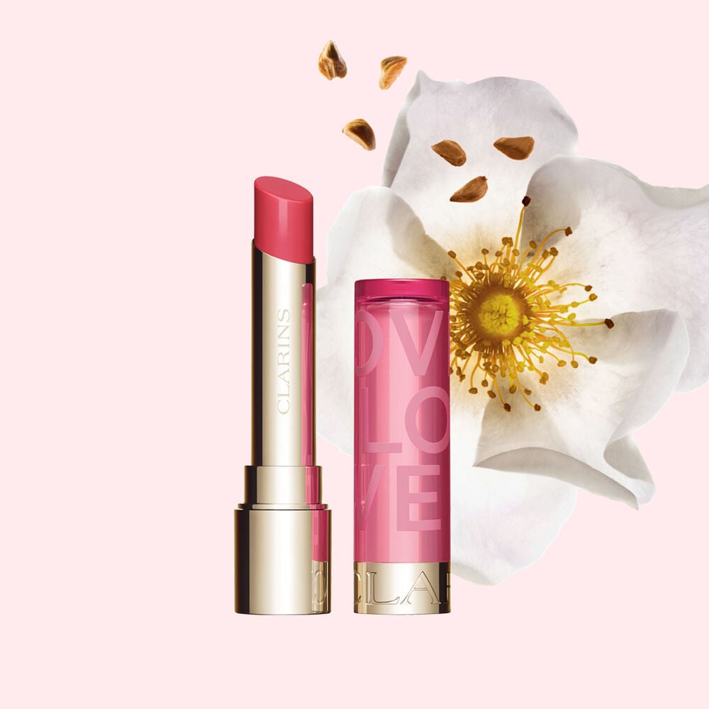 Packshot of Lip Balm Limited Edition Love Collection in front of a rose on a light pink background emphasizing its vibrant color