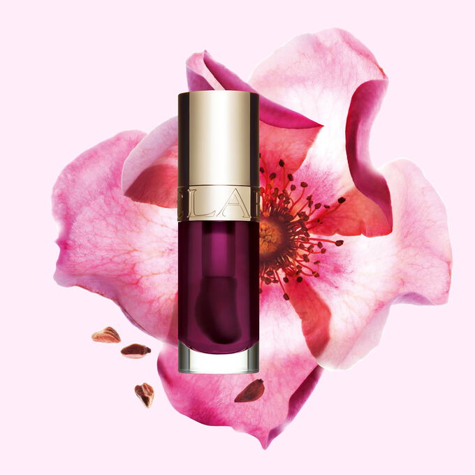 Packshot of Clarins Lip Comfort Oil Plum, placed next to a sweetbriar rose on a light pink background.