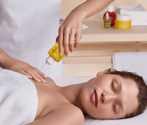 A woman lying down getting a massage with Clarins oil
