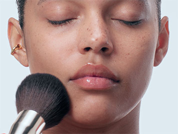 Focus on the face of a woman using a make-up brush
